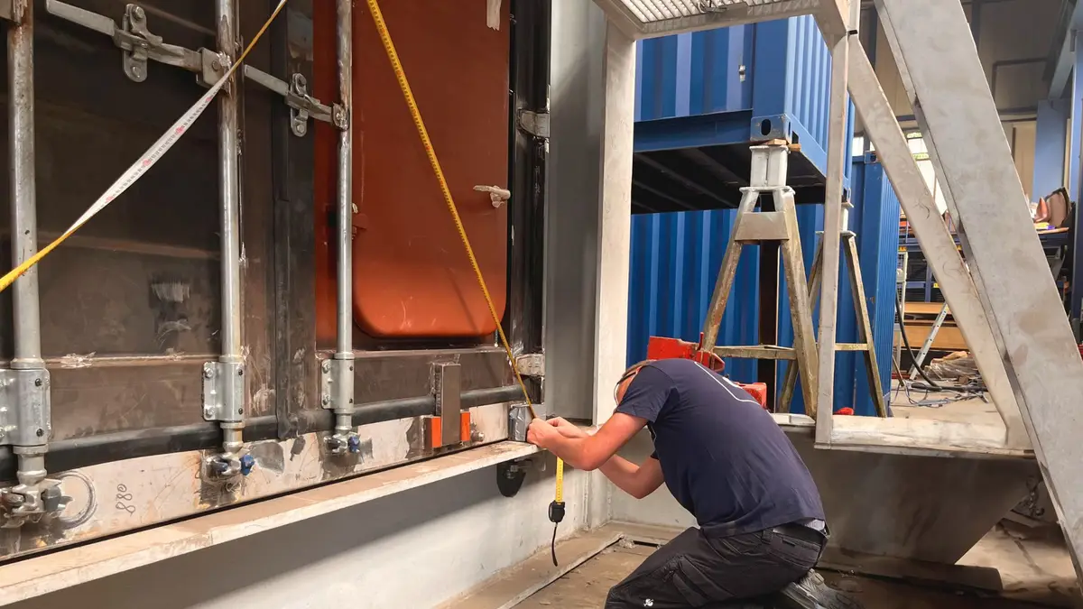 Eine Person, die bei einer CSC Prüfung bei der CHS Container Group gezeigt wird. Er hält ein Maßband an einen Container.