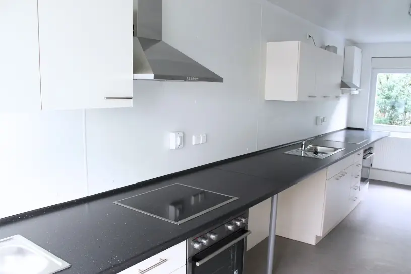 Die Innenansicht eines Küchen- und Spülcontainers. Man sieht eine Küchenzeile mit hochwertigen Geräten und einer Abzugshaube. Ein Projekt der CHS Container Group.