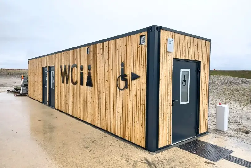 Ein Sanitärcontainer der CHS Container Group, der mit Holz von Außen verkleidet ist.