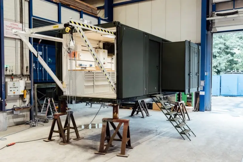 Ein Container zur militärischen Anwendung der CHS Container Group. Die vordere Seite des Containers ist geöffnet und man kann das ausgestattete Innere sehen.