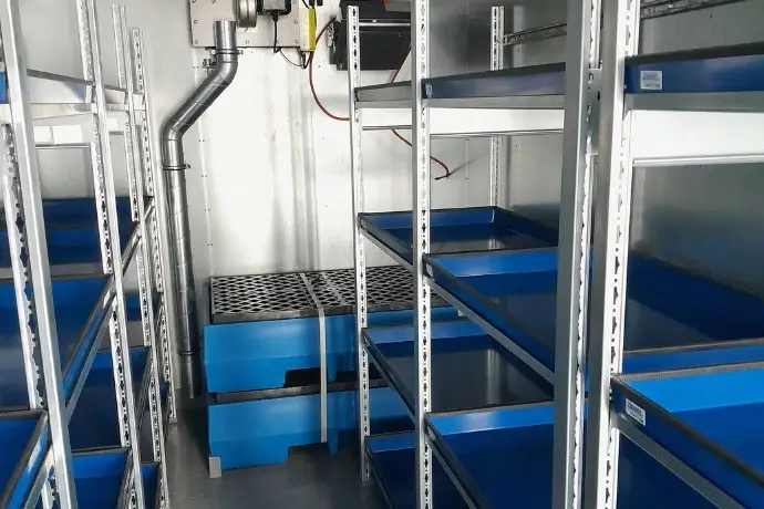 Die Innenansicht eines weißen Gefahrstofflagercontainers der CHS Container Group auf einem Schiff auf dem offenen Meer.