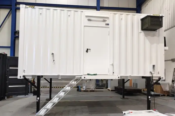 Die Außenansicht eines Containers als Mittelspannungsanlage der CHS Container Group. Der Container ist weiß und es führt eine Treppe hinauf.