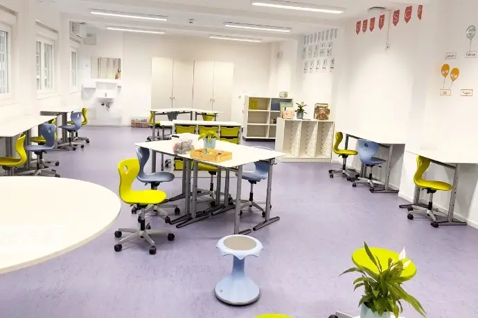 Die Inneneinrichtung des Dillener Quartiers, einer Schule, die die CHS Container Group gebaut hat. Zusehen sind mehrere Stühle an verschiedenen Tischen im Raum. 