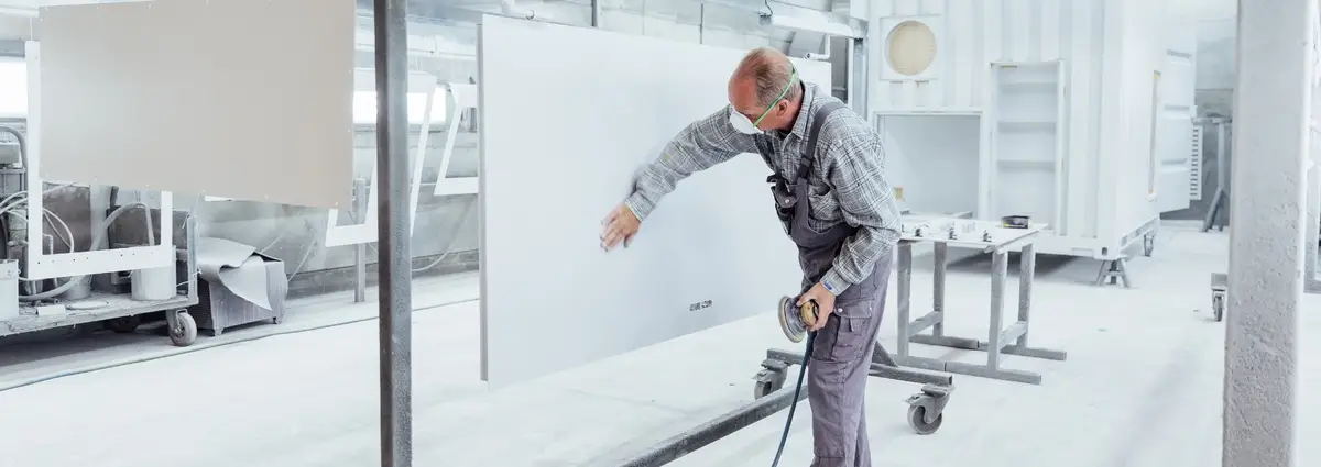 Ein Lackierer schleift eine Fläche eines Containers und schaut dabei auf seine Arbeit.