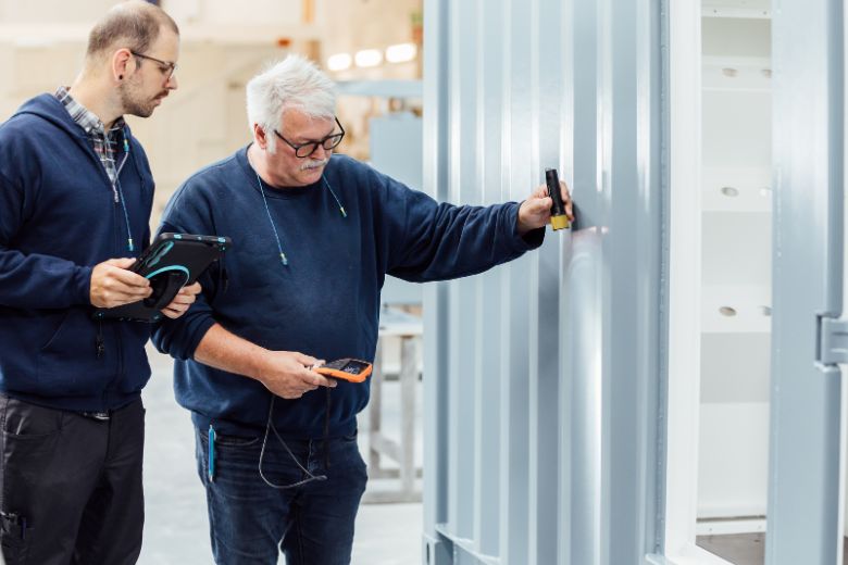 Two people from quality management are looking at a grey container