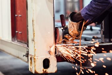 Eine Hand, die an einem Container schweißt. Die Funken fliegen.