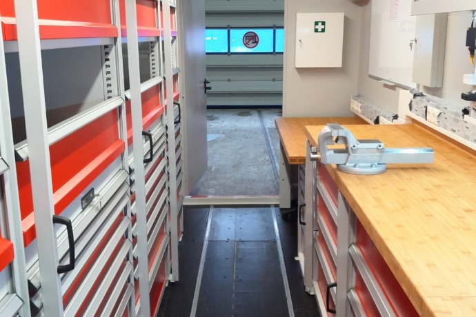 Projekt Funktionscontainer (2) Die Innenansicht eines Werkstattcontainers der CHS Container Group mit einer Werkbank und vielen Schränken zur Aufbewahrung von Werkzeugen.