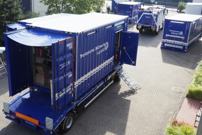 Projekt THW (3) Mehrere LKWs auf denen Werkstattcontainer geladen sind.