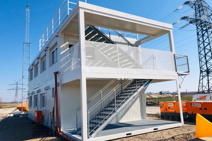 Büro (2) Aufeinander gestapelte Bürocontainer mit einer offenen Treppenansicht an der Seite auf einer Baustelle.