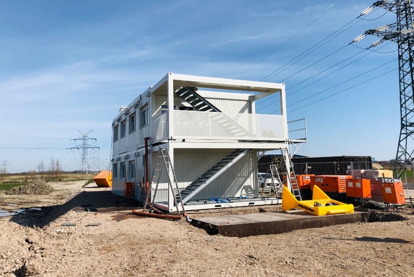Header Bürocontainer Aufeinander gestapelte Bürocontainer mit einer offenen Treppenansicht an der Seite auf einer Baustelle.