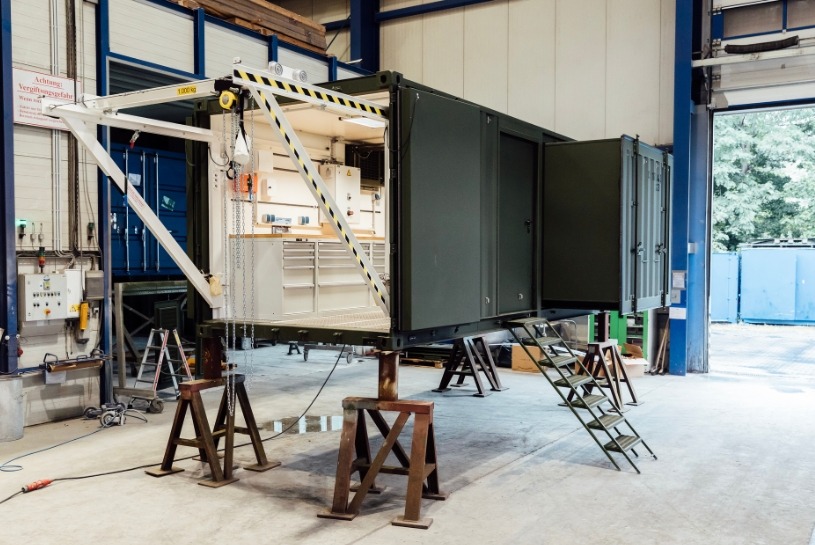 Ein Container zur militärischen Anwendung der CHS Container Group. Die vordere Seite des Containers ist geöffnet und man kann das ausgestattete Innere sehen.