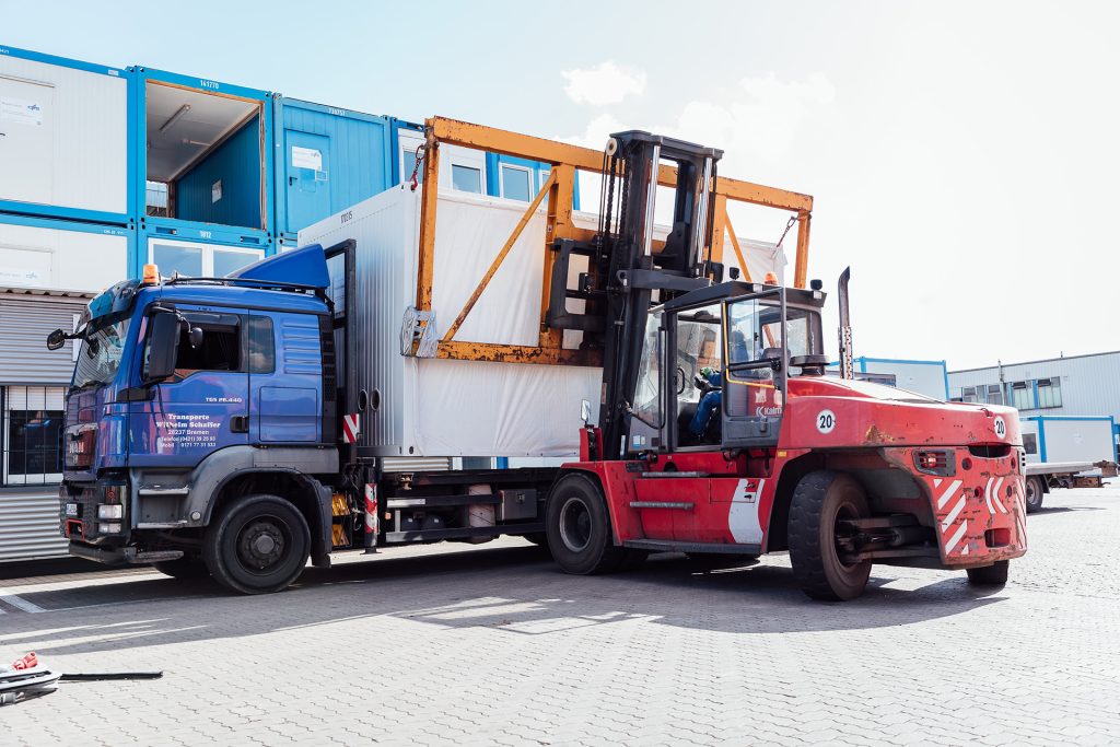 Ein Gabelstapler, der einen Container von einem LKW herunterholt auf dem Containerdepot der CHS Container Group