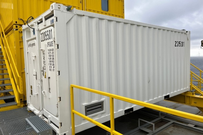 Projekt Gefahrstofflagercontainer (1) Die Außenansicht eines weißen Gefahrstofflagercontainers der CHS Container Group auf einem Schiff auf dem offenen Meer.