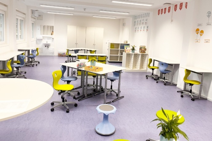 Schule (2) Die Inneneinrichtung des Dillener Quartiers, einer Schule, die die CHS Container Group gebaut hat. Zusehen sind mehrere Stühle an verschiedenen Tischen im Raum.