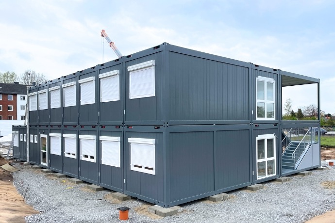 Schule (3) Mehrere übereinandergestapelte Bürocontainer in einem dunkelgrau.