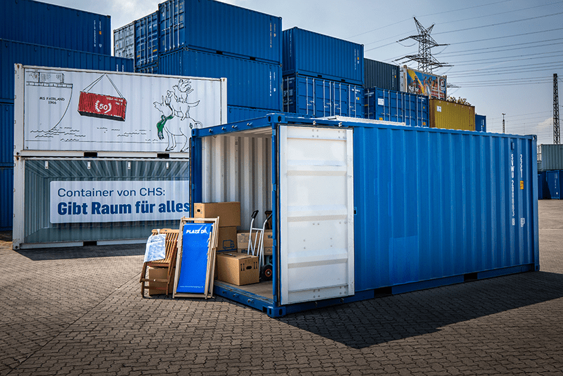 Storagecontainer auf dem Depot der CHS Container Group mit geöffneten Türen. Darin stehen verschiedene Kartons, Klappstühle und eine Sackkarre
