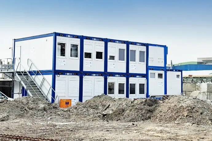 Mehrere Bürocontainer, die auf einer Baustelle übereinander gestapelt wurden.