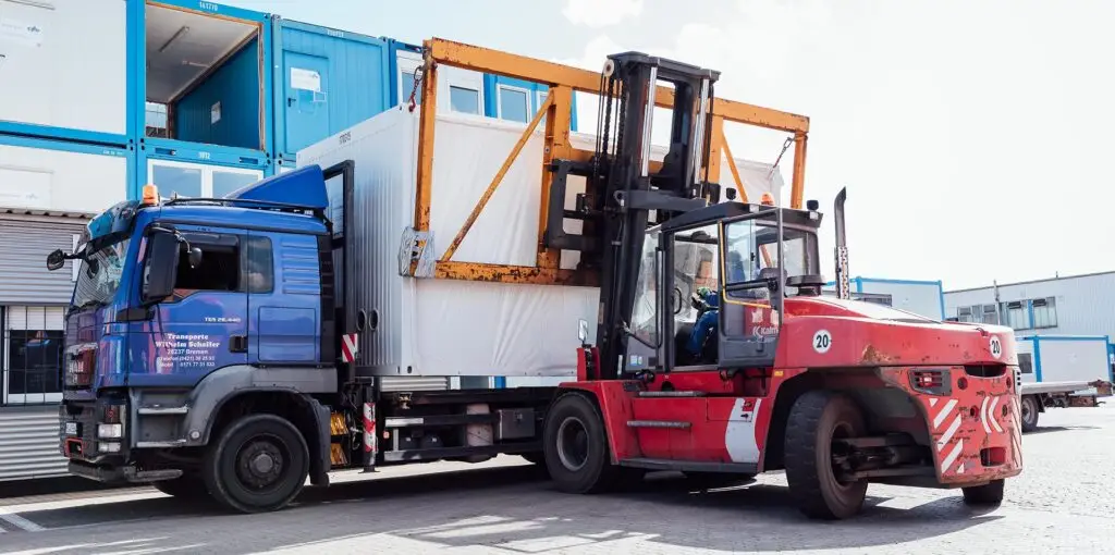 Ein Gabelstapler, der einen Container von einem LKW herunterholt auf dem Containerdepot der CHS Container Group
