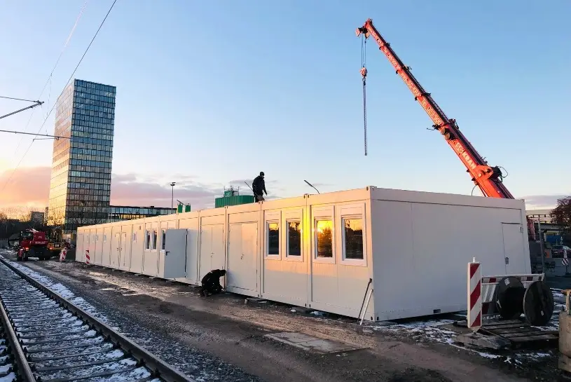 Mehrere Bürocontainer der CHS Container Group auf einer Baustelle. Im Hintergrund sieht man einen Kran, ein Hochhaus und Gleise vor den Bürocontainern.