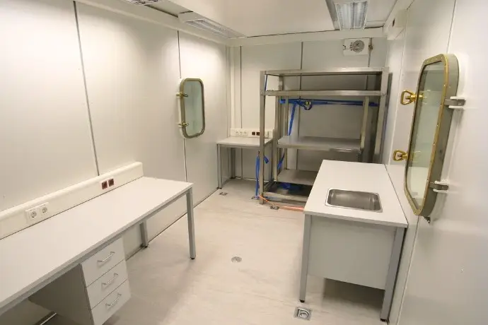 Die Innenansicht eines Schiffslabor der CHS Container Group. Man sieht mehrere Tische, Regal und zwei Fenster an den Seiten des Containers.