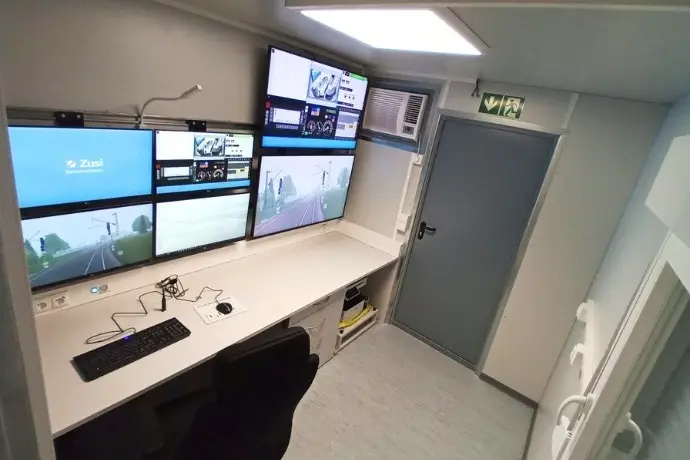 Die Innenansicht eines Simulatorcontainers der CHS Container Group. Man sieht einen Tisch an dem ein Stuhl steht und davor mehrere Monitore für die Simulation.