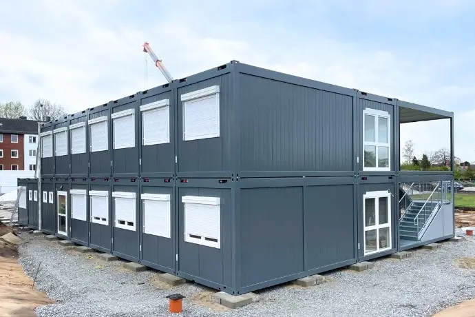 Mehrere übereinandergestapelte Bürocontainer in einem dunkelgrau.