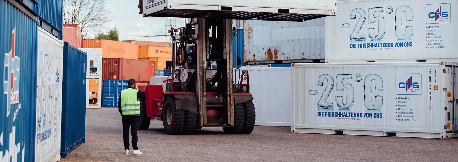 Ein Kühlcontainer, der auf einem Gabelstapler über ein Containerdepot gefahren wird.