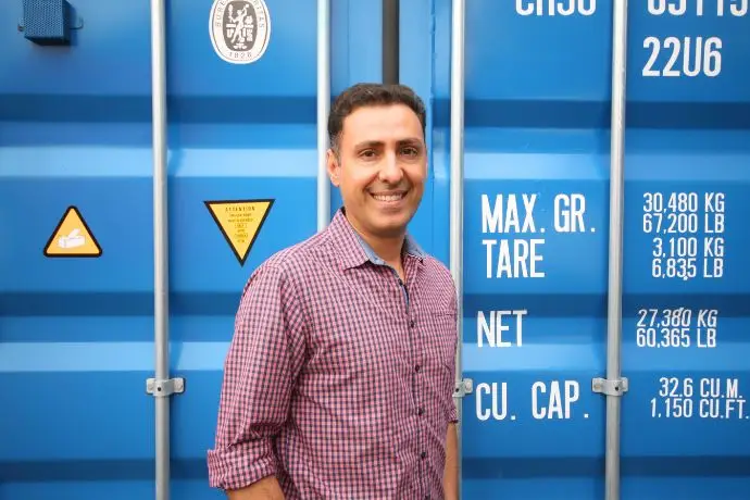 Design ohne Titel (58) Eine männliche Person steht vor einem Container und lächelt in die Kamera, Iman Hashemi