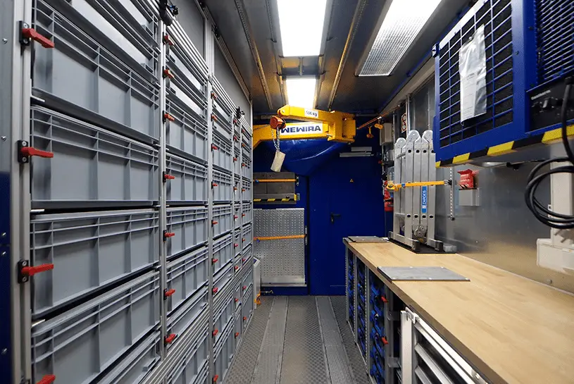 Werkstattcontainer-von-CHS Innenansicht eines Werkstattcontainers der CHS Container Group mit mehreren Werkarbeitsplatten und Regalen