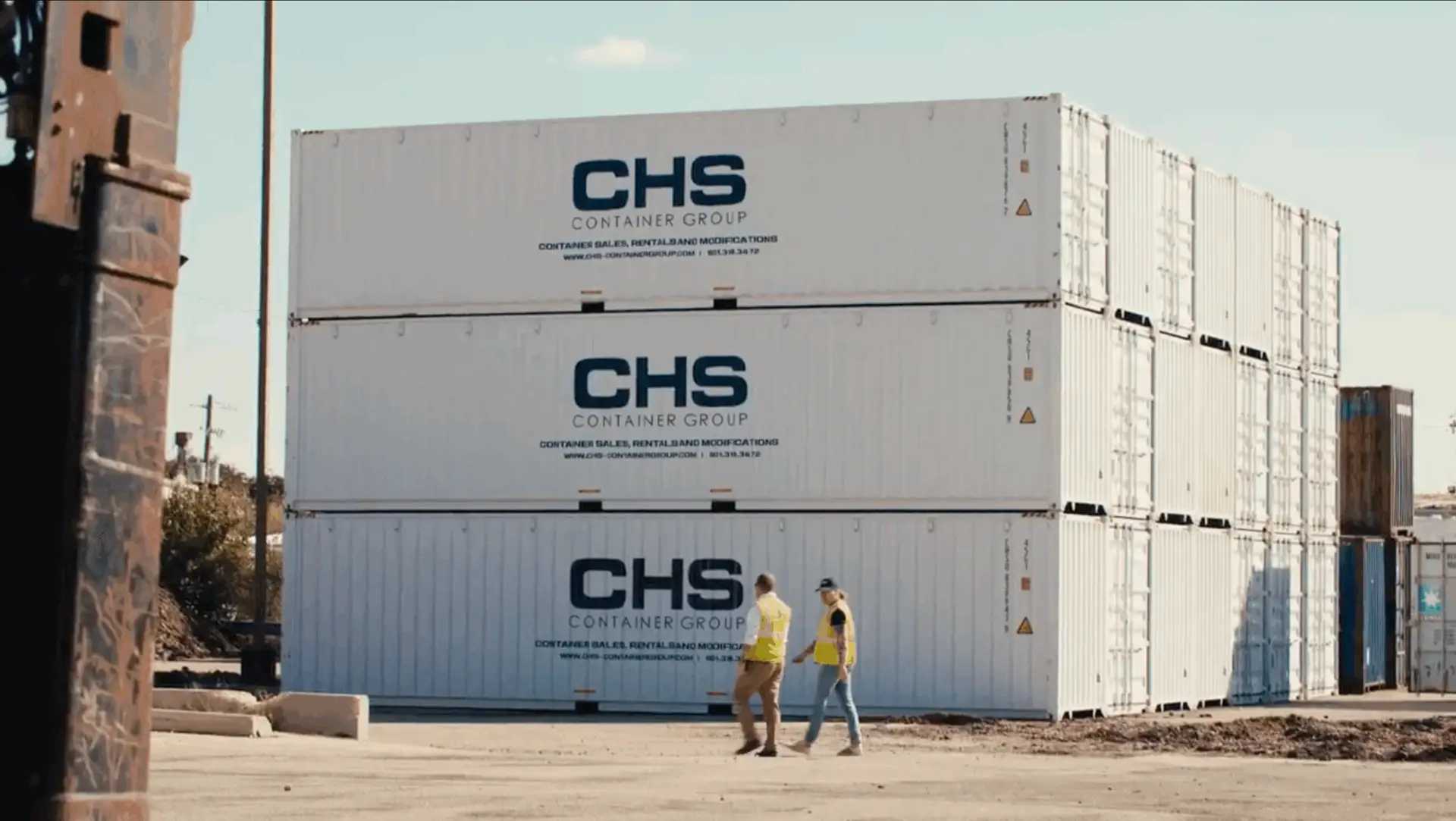 CHS team members walk alongside a stack of CHS-branded shipping containers.