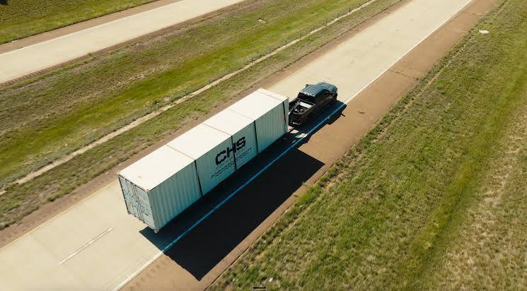 Birdseye view of a CHS-branded container being deilvered by a tilt-bed trailer.