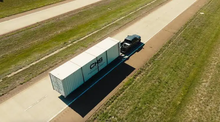 Birdseye view of a CHS-branded container being deilvered by a tilt-bed trailer.